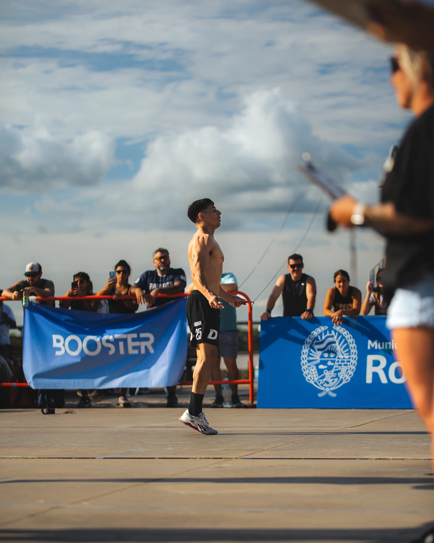 Atleta saltando la soga frente a la bandera de Booster en Rosario Fitness Games