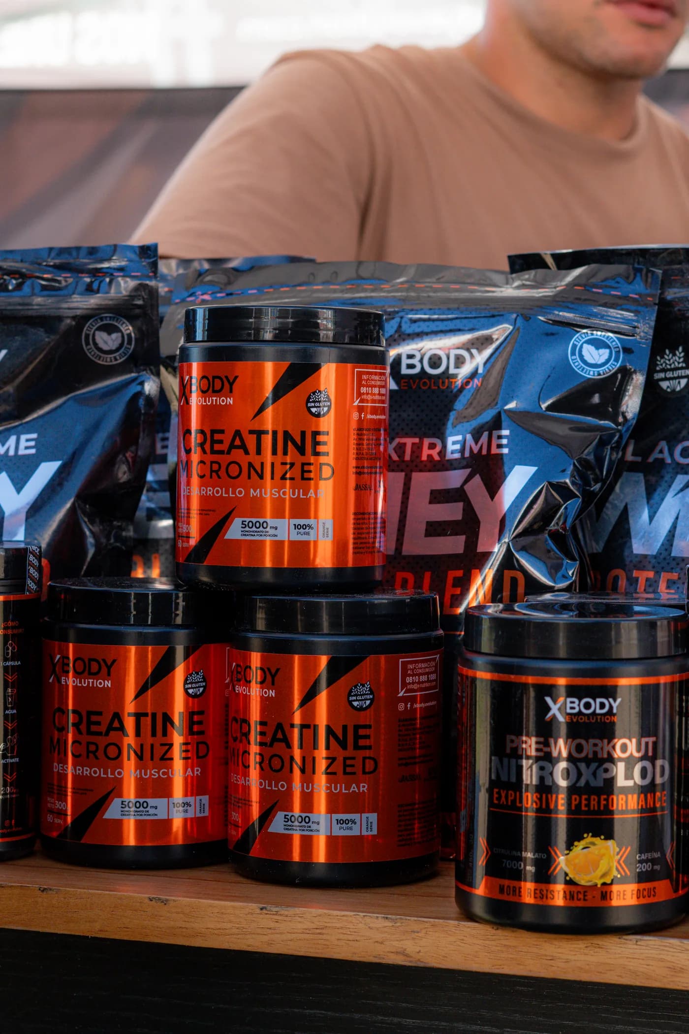 Creatina, pre-entreno y proteína de Xbody Evolution sobre el mostrador del puesto