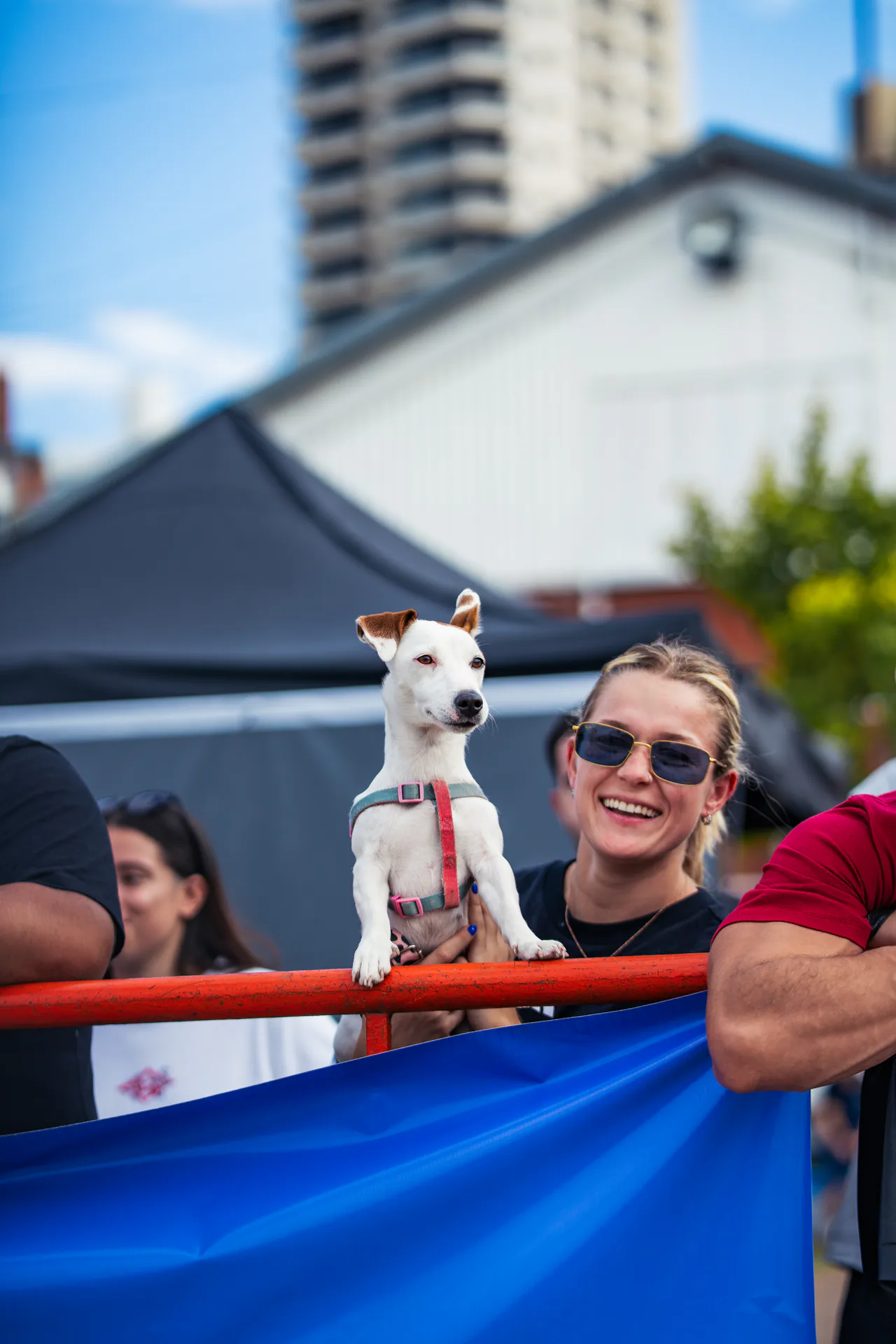 Espectadora sonriendo junto a su perro detrás de la valla